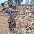 A woman stands over what was left of her house after the NEMA operation