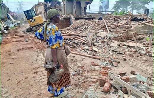A woman stands over what was left of her house after the NEMA operation