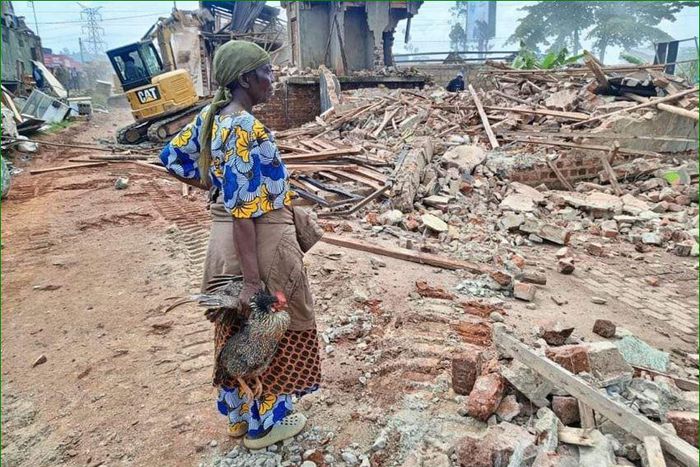 A woman stands over what was left of her house after the NEMA operation