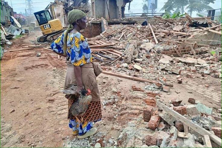 A woman stands over what was left of her house after the NEMA operation