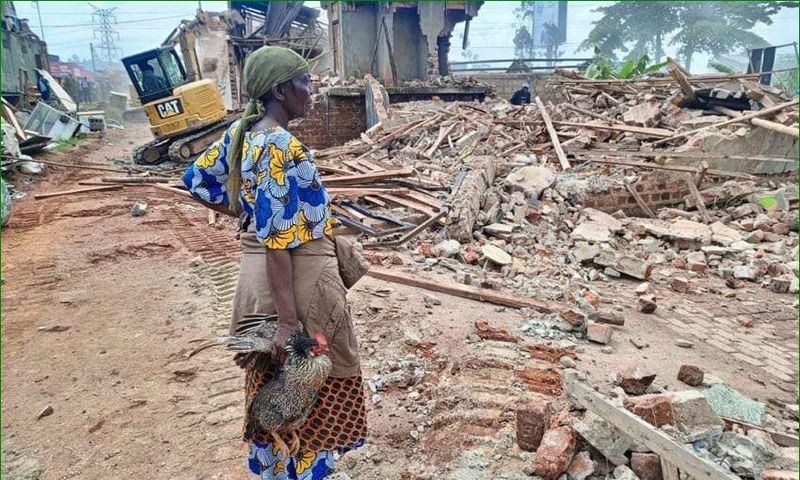 A woman stands over what was left of her house after the NEMA operation
