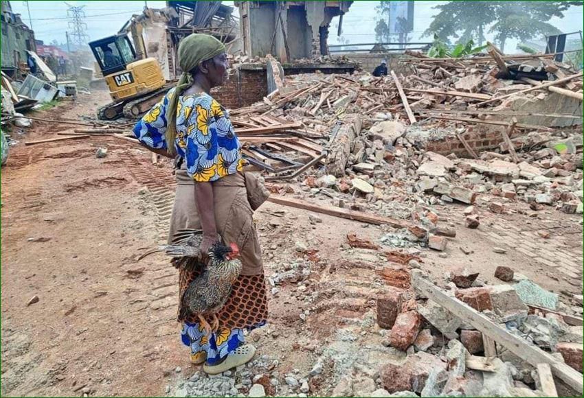 A woman stands over what was left of her house after the NEMA operation
