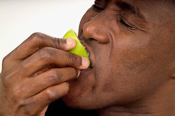 Close-up of a man biting into a lemon half