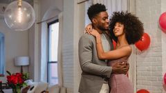 Couple dancing while hugging in a room near the table