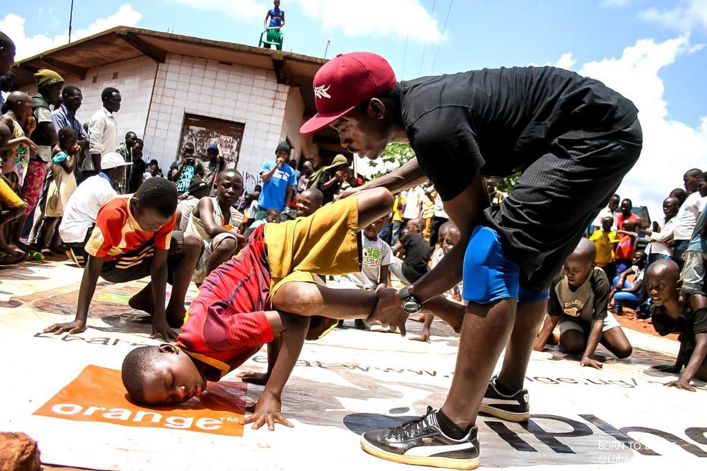Kaweesi teaches a child some breakdance moves