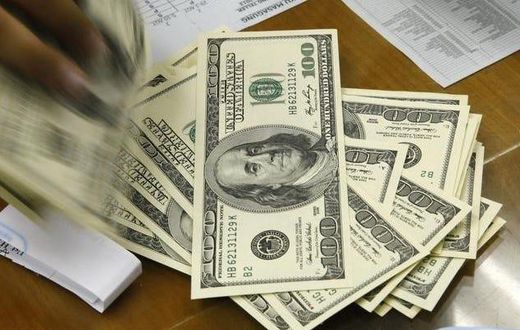 A money changer holds stacks of US dollar notes in JakartaThomson Reuters