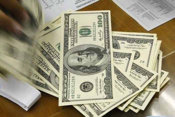 A money changer holds stacks of US dollar notes in JakartaThomson Reuters