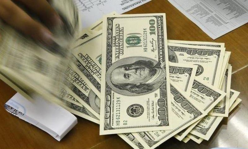 A money changer holds stacks of US dollar notes in JakartaThomson Reuters