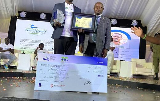 Ssentogo posing with his award. Besides him is the Iganga District Resident Judge, Justice David Batema