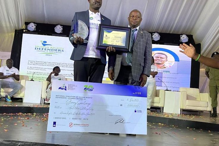 Ssentogo posing with his award. Besides him is the Iganga District Resident Judge, Justice David Batema