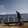A construction worker walks past solar panels installed in Xinjiang, China.VCG /Getty Images