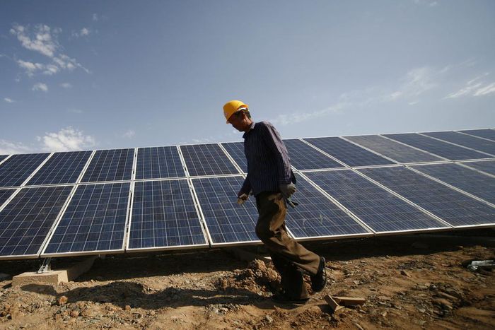 A construction worker walks past solar panels installed in Xinjiang, China.VCG /Getty Images