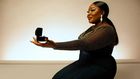 AI-generated image of an African woman, elegantly kneeling in a stylish dinner dress