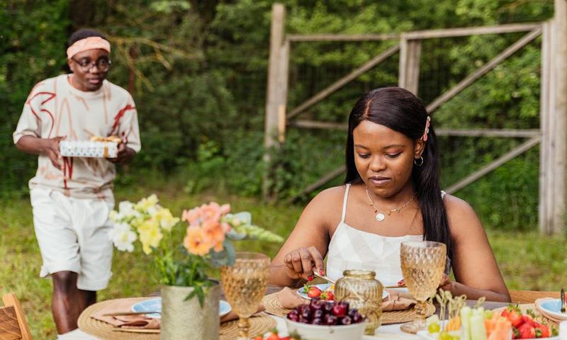 Couple on an outdoor date with the man holding a surprise gift [Image Credit: Antoni Shkraba Production]