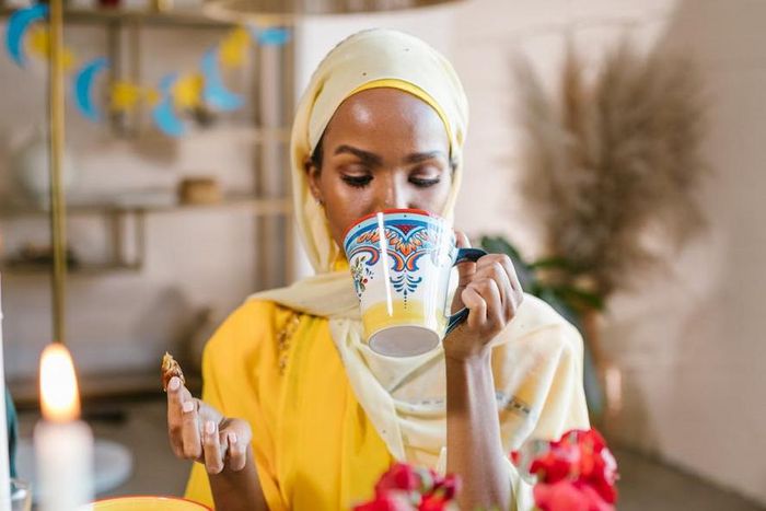 Woman in yllow hijab eating and drinking during Ramdhan [Image Credit: RDNE Stock Project]