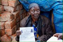 A woman shows proof of land ownership after her house was razed down by NEMA