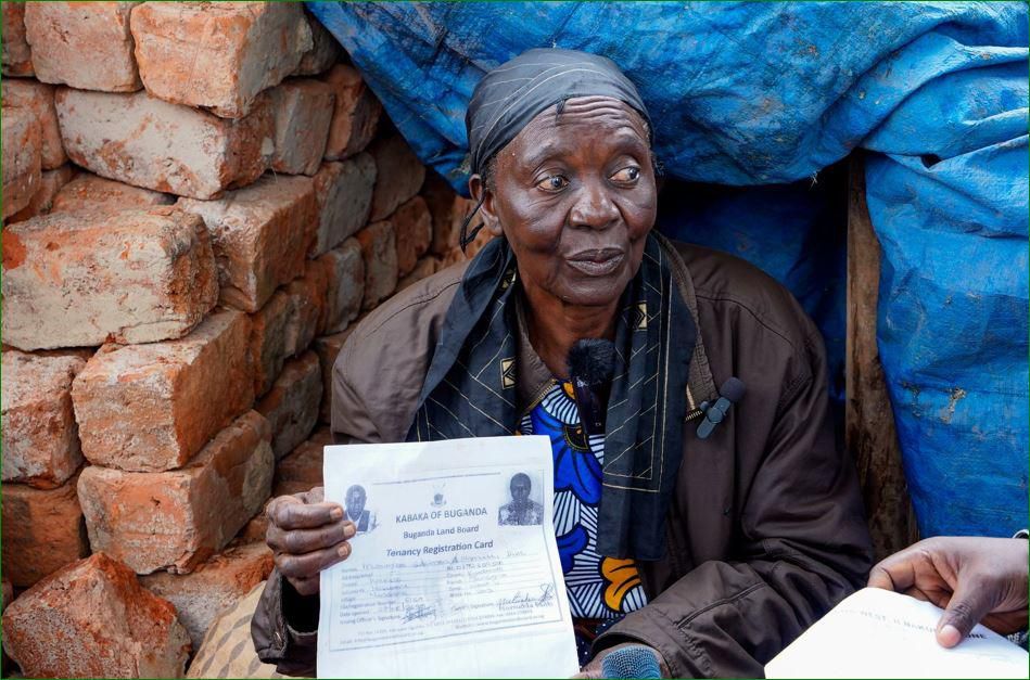 A woman shows proof of land ownership after her house was razed down by NEMA