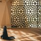 Woman praying in a mosque with openwork windows {image Credit: Hatice Baran]