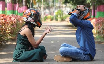 Photo of a couple wearing helmets, sitting on a pavement in a park [Image Credit: Professional QP]