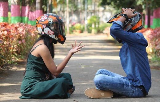 Photo of a couple wearing helmets, sitting on a pavement in a park [Image Credit: Professional QP]