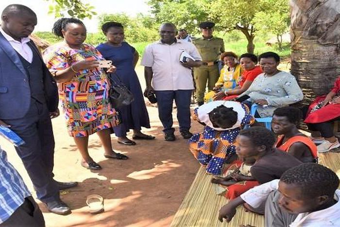 MPs on the Committee of Health interacting with a family (seated) caring for children with Nodding Disease