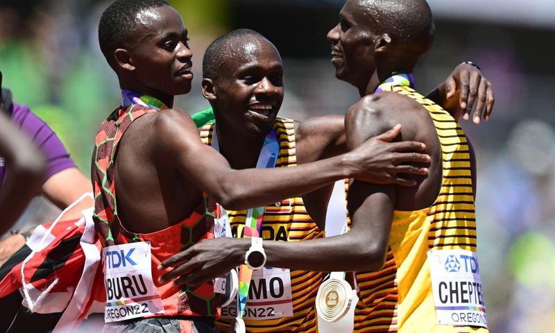EUGENE, OREGON - JULY 17: Gold medalist Joshua Cheptegei of Team Uganda, silver medalist Stanley Waithaka Mburu of Team Kenya and bronze medalist Jacob Kiplimo of Team Uganda celebrate after the Men's 10,000m Final on day three of the World Athletics C...