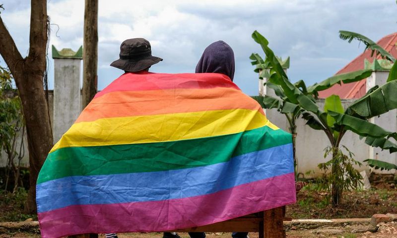 A gay Ugandan couple cover themselves with a pride flag as they pose for a photograph in Uganda Saturday, March 25, 2023.AP Photo