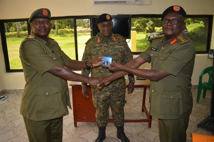 Lt Col Moses Kaggwa recieves office stamps from Col Tom Musoke as the 4Inf Division Commander looks on