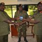 Lt Col Moses Kaggwa recieves office stamps from Col Tom Musoke as the 4Inf Division Commander looks on