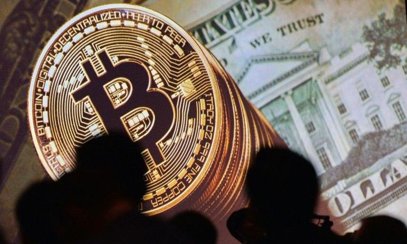 A screen displays images of Bitcoin and US dollars at the Interpol World Congress in Singapore on July 4, 2017