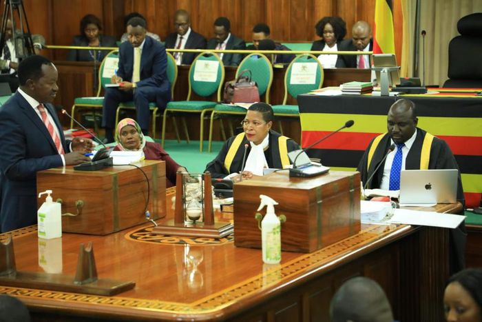 Wilson Kajwengye (L) speaking during the Committee of the Whole House on Tuesday, April 23. Speaker, Anita Among (C) and a staff of Parliament (R) are at the Clerk’s Table