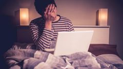 Sad man in bed with laptop