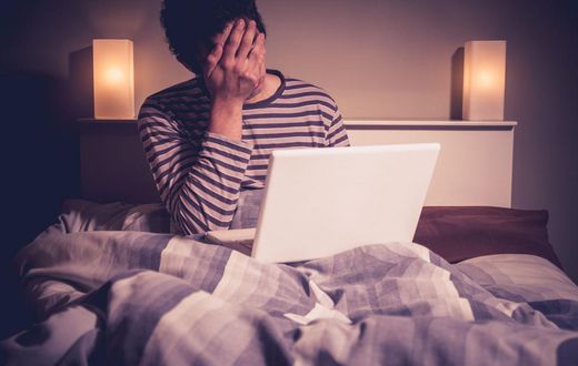 Sad man in bed with laptop