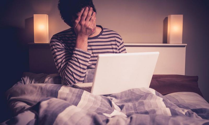 Sad man in bed with laptop