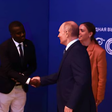 Davis Akampulira shakes hands with Russian President Vladimir Putin