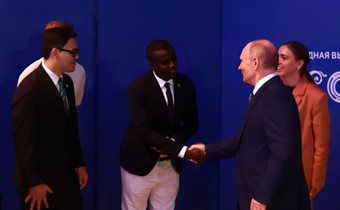 Davis Akampulira shakes hands with Russian President Vladimir Putin