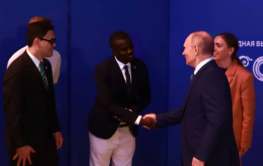Davis Akampulira shakes hands with Russian President Vladimir Putin