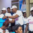 Ministry of Health Spokesperson Mr. Emmanuel Ainebonya, Group Chief Category and Innovations Officer Mrs Toluwaleke and Head of Marketing and Corporate Affairs, Mr. Robert Kitenda (C) handing over the items to young mothers at Kawempe National Referral...
