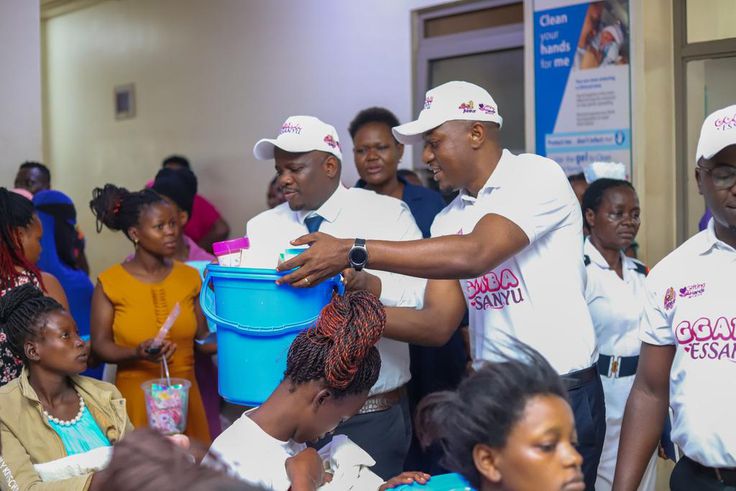 Ministry of Health Spokesperson Mr. Emmanuel Ainebonya, Group Chief Category and Innovations Officer Mrs Toluwaleke and Head of Marketing and Corporate Affairs, Mr. Robert Kitenda (C) handing over the items to young mothers at Kawempe National Referral...