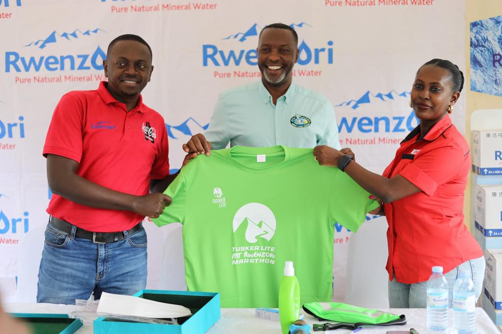 Amos Wekesa together with CCBU's  Innocent Namanya and Pearl Nimusiima unveiling the Rwenzori Marathon kit