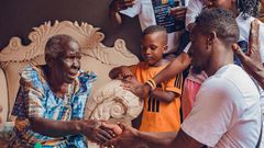 Rickman Manrick shakes hands with an elderly woman while in Bakuli, Kampala. Image credit: Bryan Morel Publications.