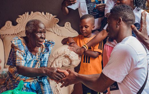 Rickman Manrick shakes hands with an elderly woman while in Bakuli, Kampala. Image credit: Bryan Morel Publications.