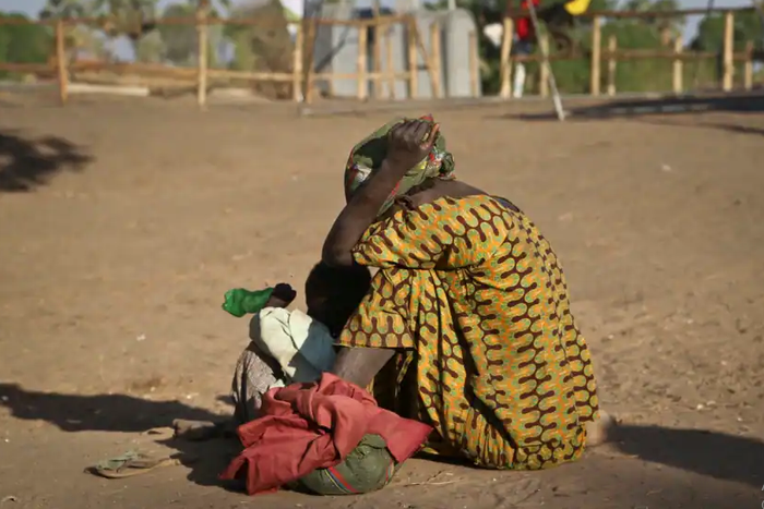 A South Sudanese refugee woman sits with her child at a refugee collection center in Palorinya (courtesy)