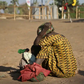 A South Sudanese refugee woman sits with her child at a refugee collection center in Palorinya (courtesy)