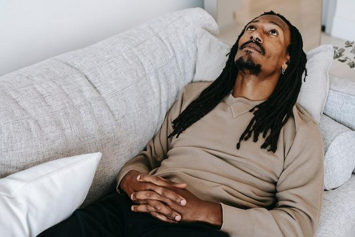 Pensive black man lying on couch [Photo: Alex Green]