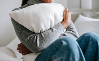 Unrecognisable woman embracing a pillow in a bedroom [Image Credit: Alex Green]