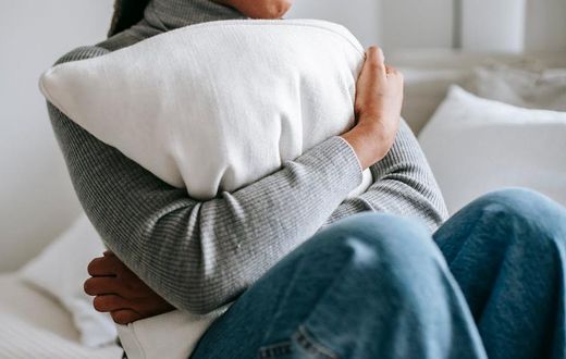 Unrecognisable woman embracing a pillow in a bedroom [Image Credit: Alex Green]