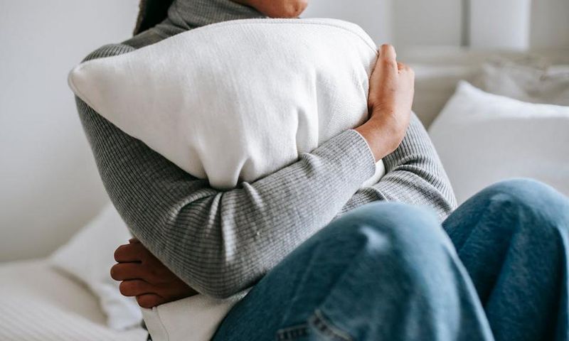 Unrecognisable woman embracing a pillow in a bedroom [Image Credit: Alex Green]