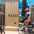 Boda boda rider securing television screen on bike/Courtesy