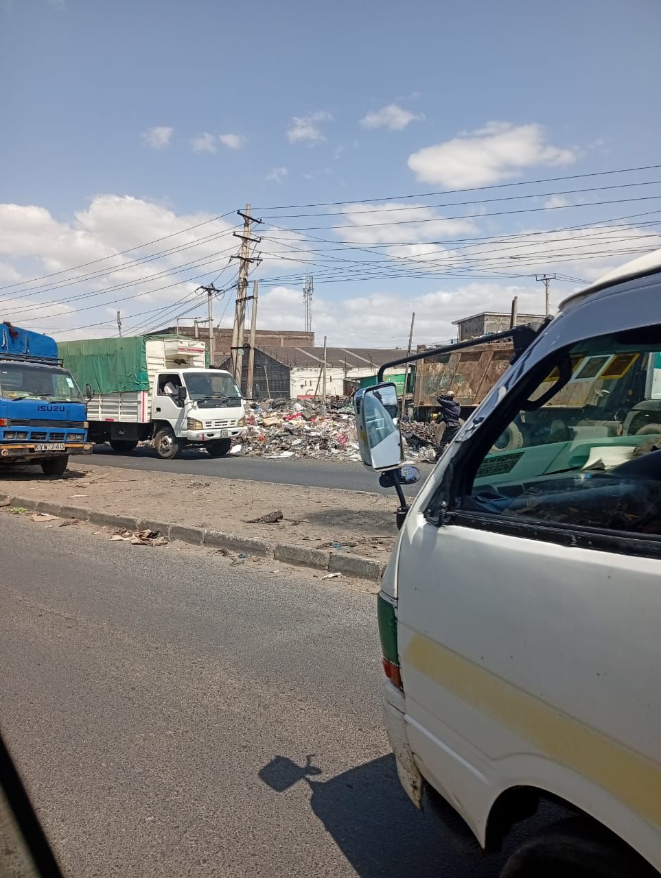 Vehicles driving past a pile of garbage along Enterprise Road, Nairobi
